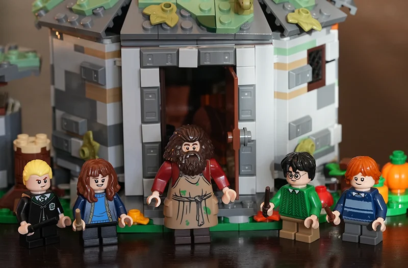 Lego-figuren van personages uit Harry Potter staan voor een gedetailleerd Lego-model van een huisje.