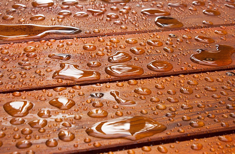 Waterdruppels op geïmpregneerd houten oppervlak, dat waterafstotend is gemaakt.